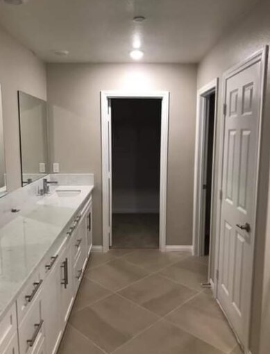 Bathroom with fresh greige walls, white doors and trim beside a double vanity