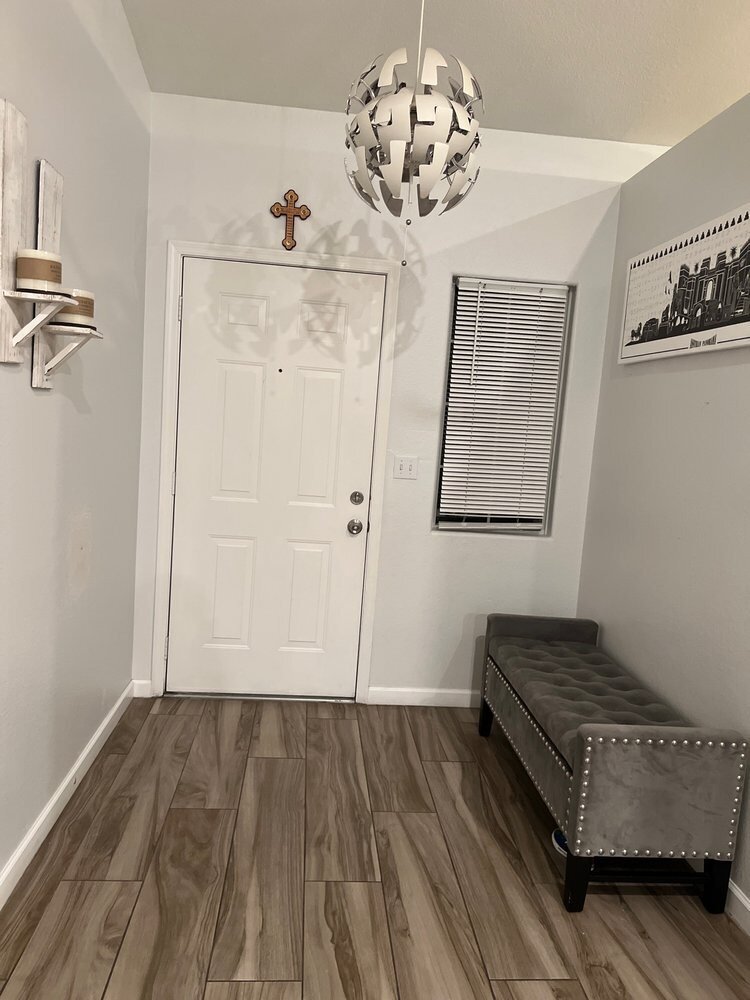 Entry hall with light gray walls, a white six-panel front door and white baseboards
