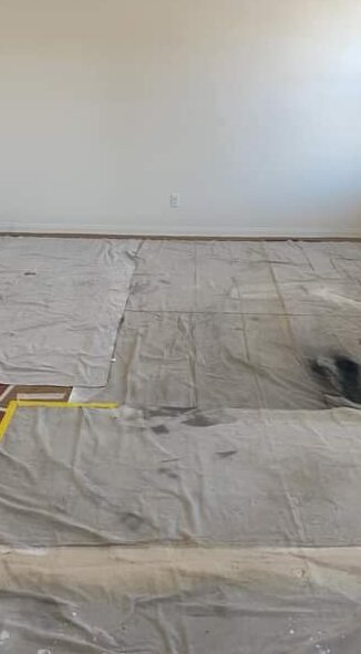 Empty room with the whole floor covered in canvas drop cloths taped at the edges