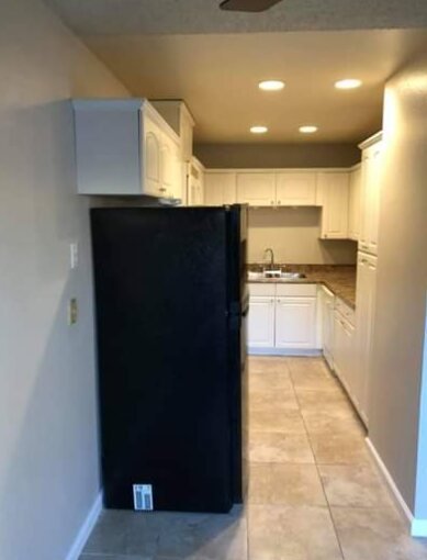 Narrow kitchen with freshly painted beige walls and white cabinets